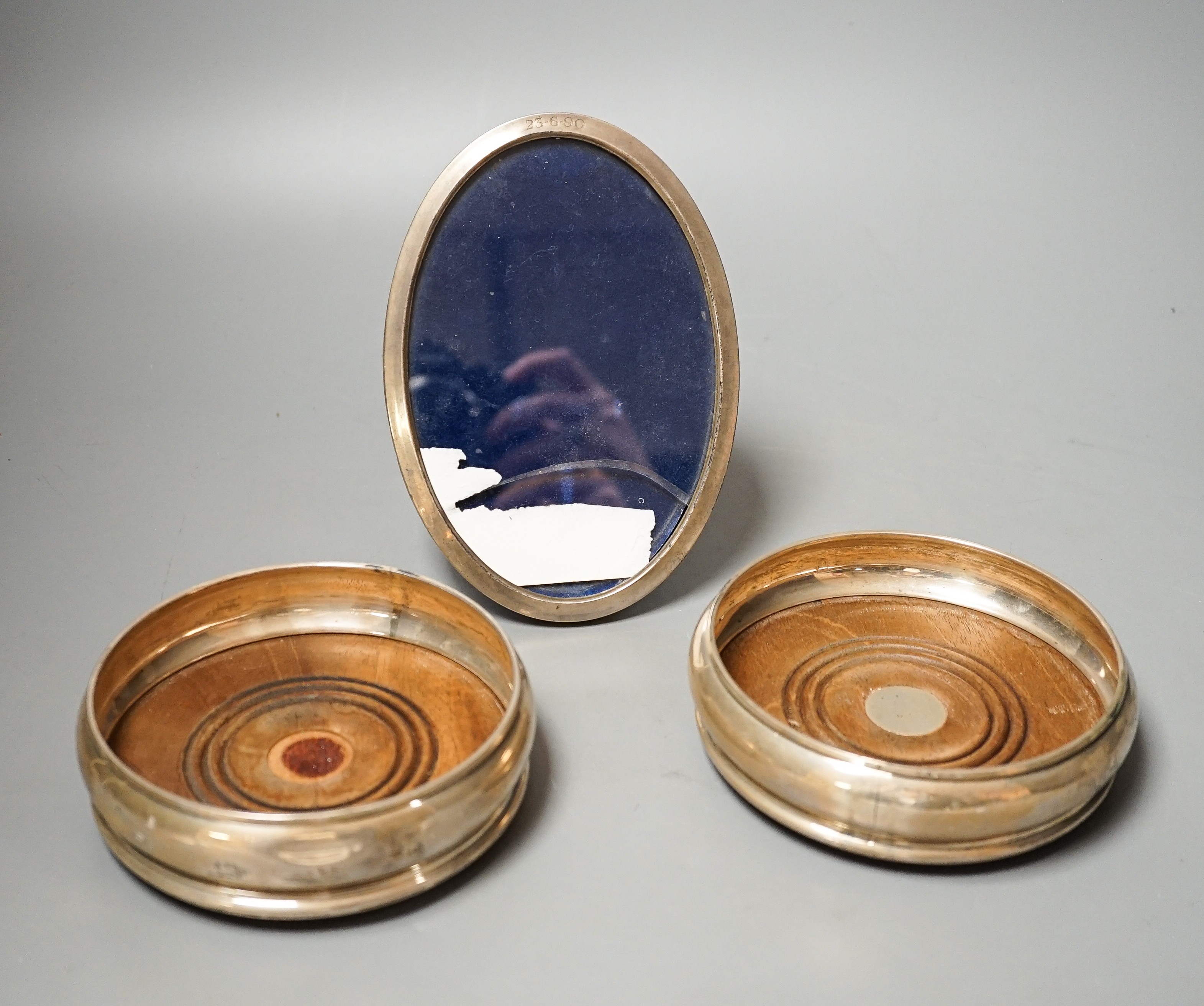 A pair of modern silver mounted wine coasters, W.E.V. London, 1990, (a.f.), 12.2cm and a 925 mounted oval photograph frame.